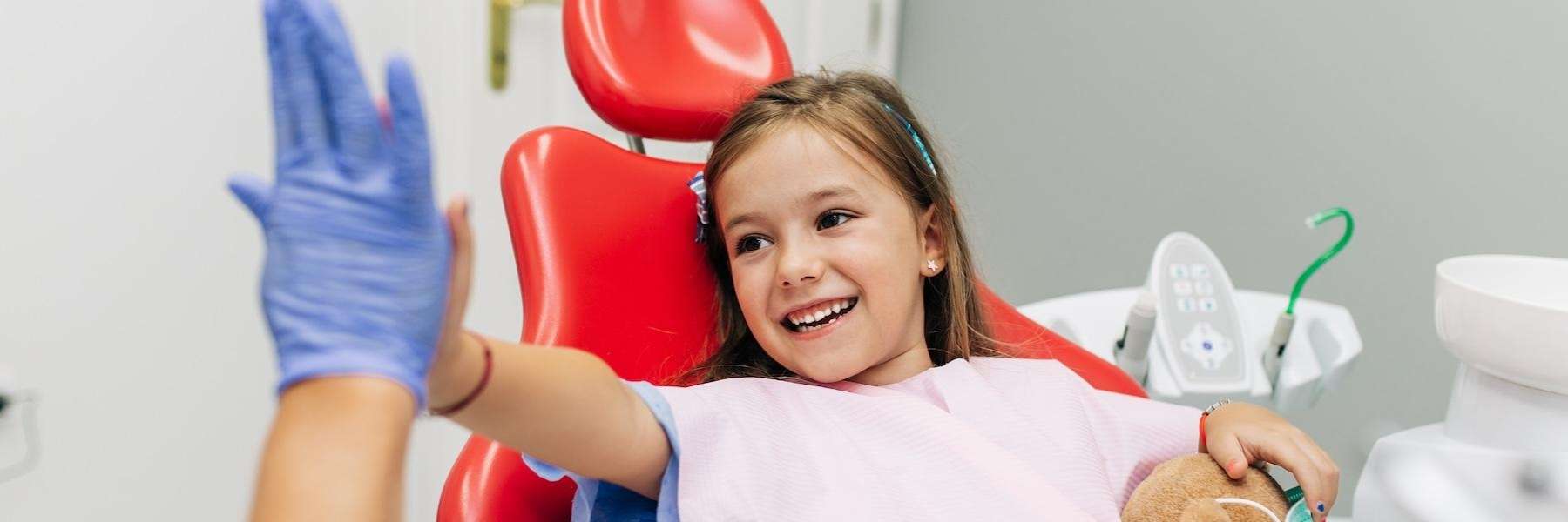 A small girl high-fiving her dentist