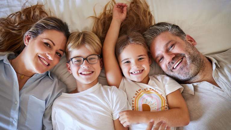 A family smiling in bed
