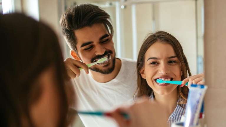 A couple brushing their teeth together