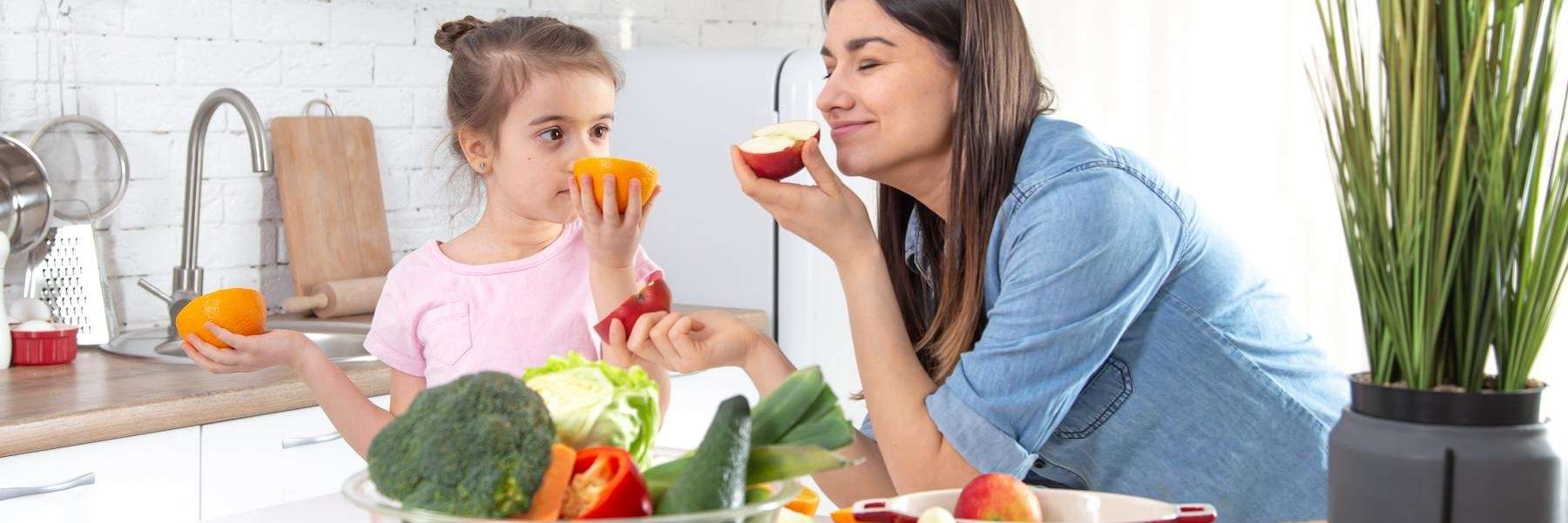 A mother and daughter eating fruits and vegetables